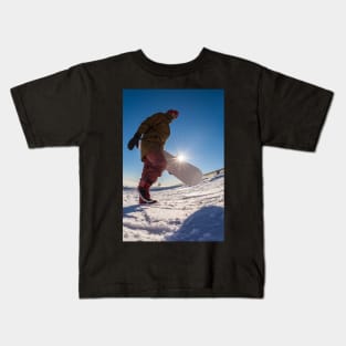 Snowboarder walking against blue sky Kids T-Shirt